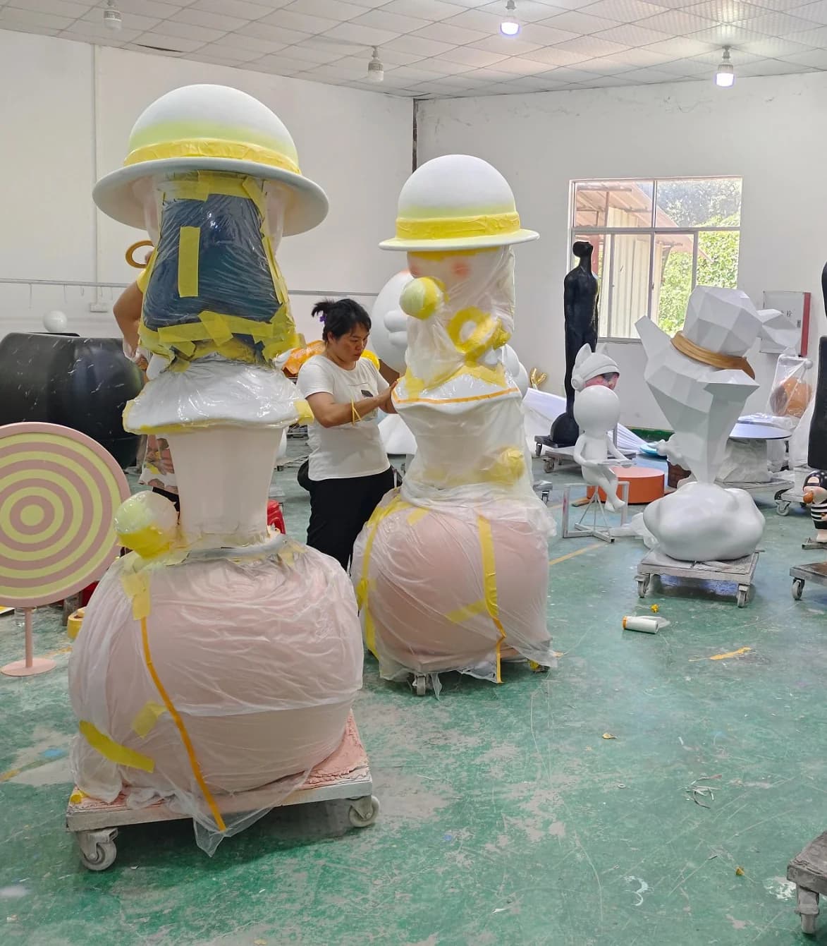 Worker applying masking tape and protective film to custom sculptures in the YAVIS workshop