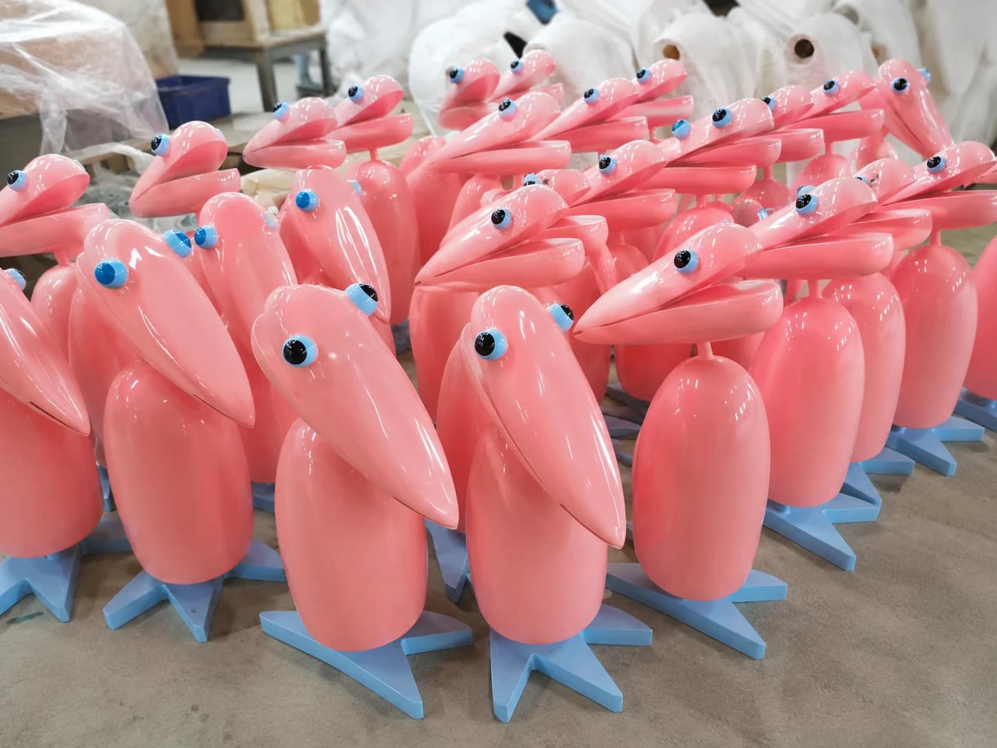 Multiple pink sculptural bird props produced as a repeated batch in a fabrication workshop.