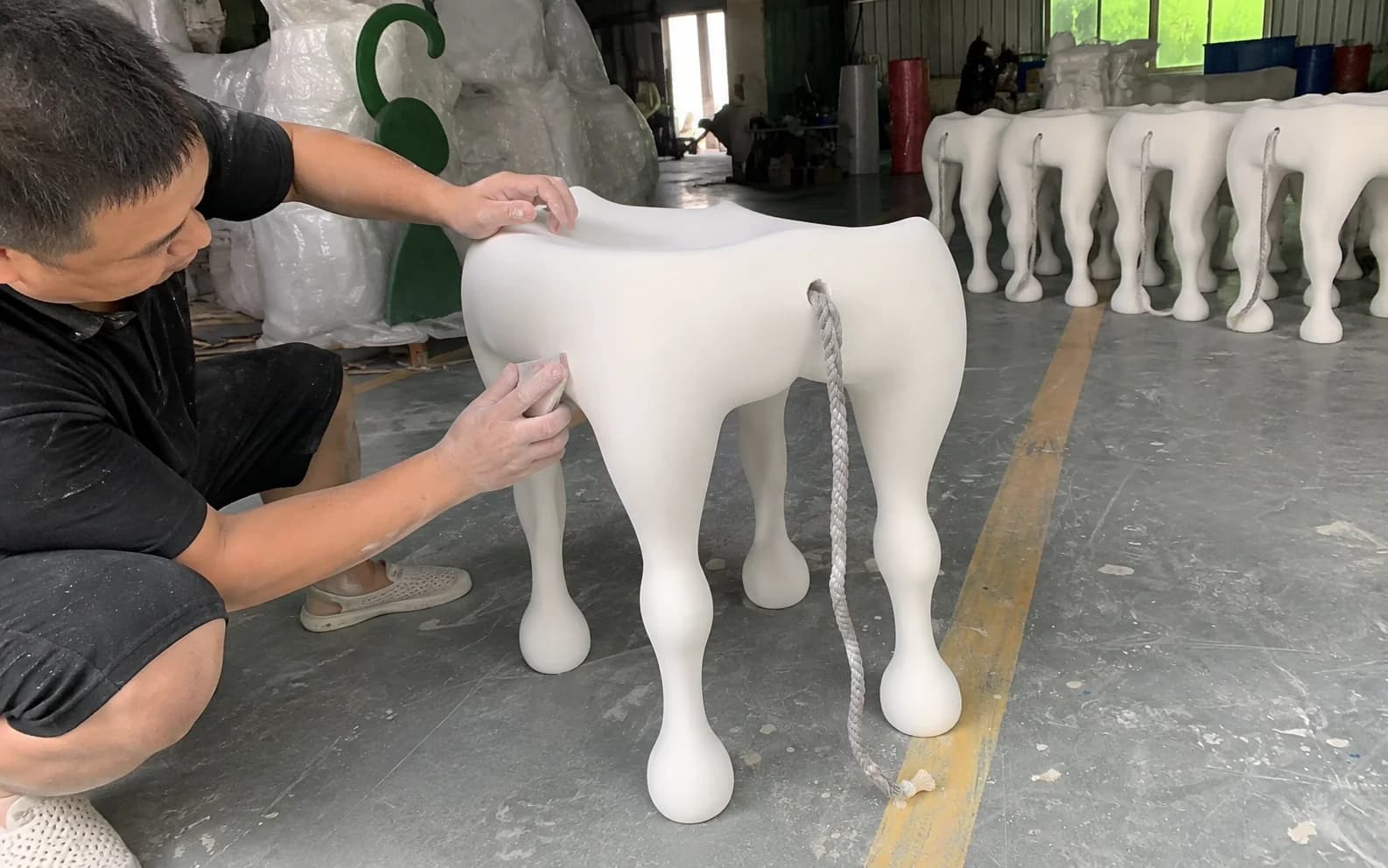 Worker finishing the surface of a sculptural seating piece before final painting.