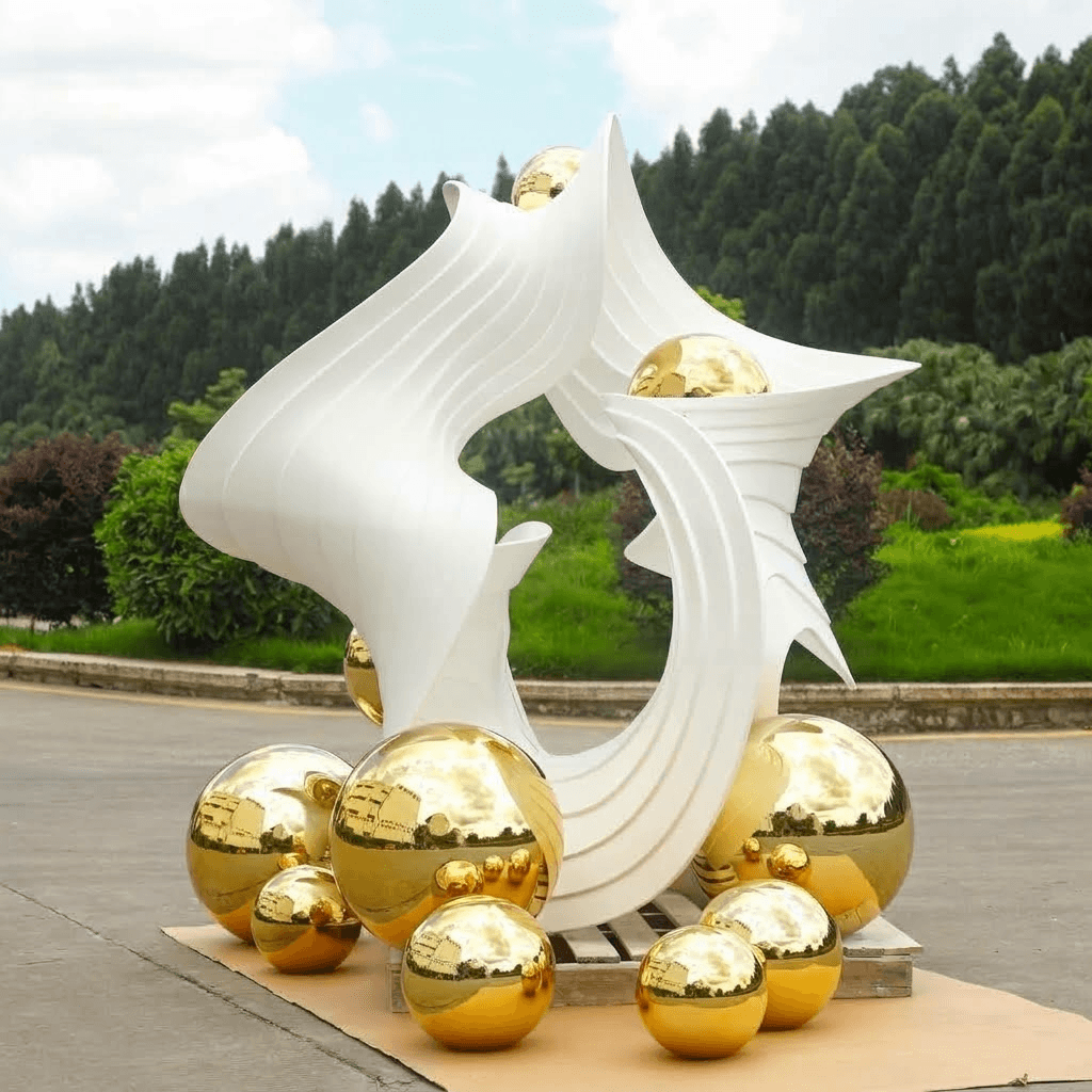 Complex-form sculptural display with white layered surfaces and mirrored gold spheres, outdoor finished piece