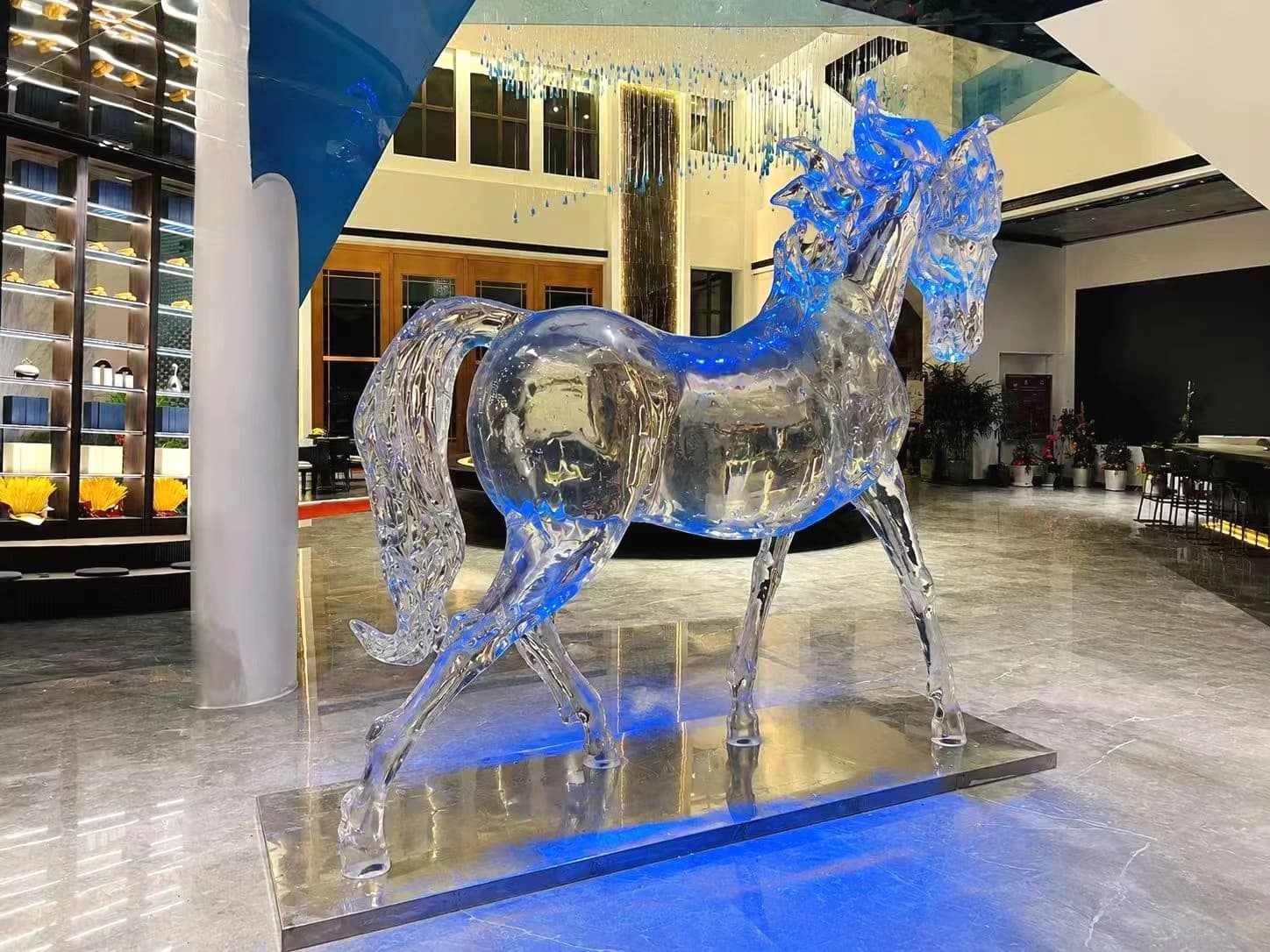Large transparent horse sculpture shown in a commercial interior setting