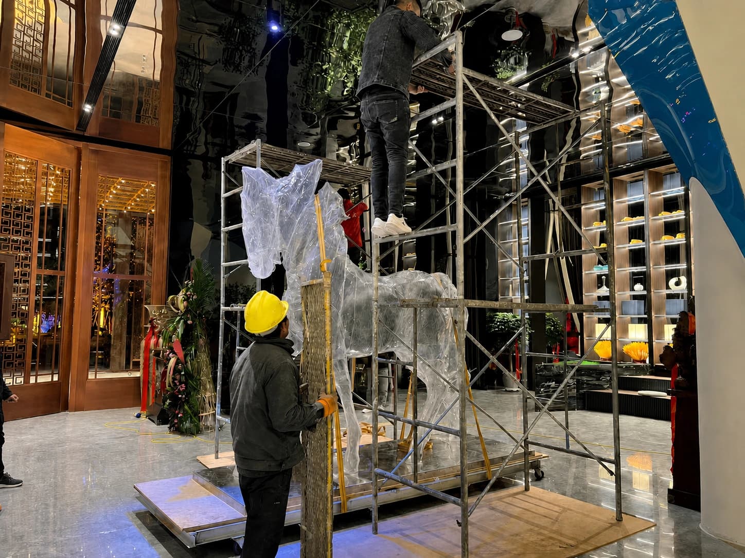 Workers installing a large transparent horse sculpture on site