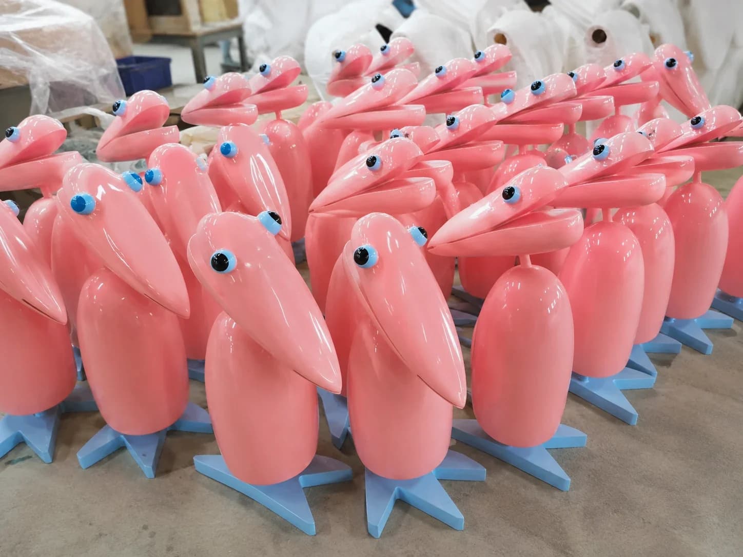 Multiple pink sculptural bird props produced as a repeated batch in a fabrication workshop.