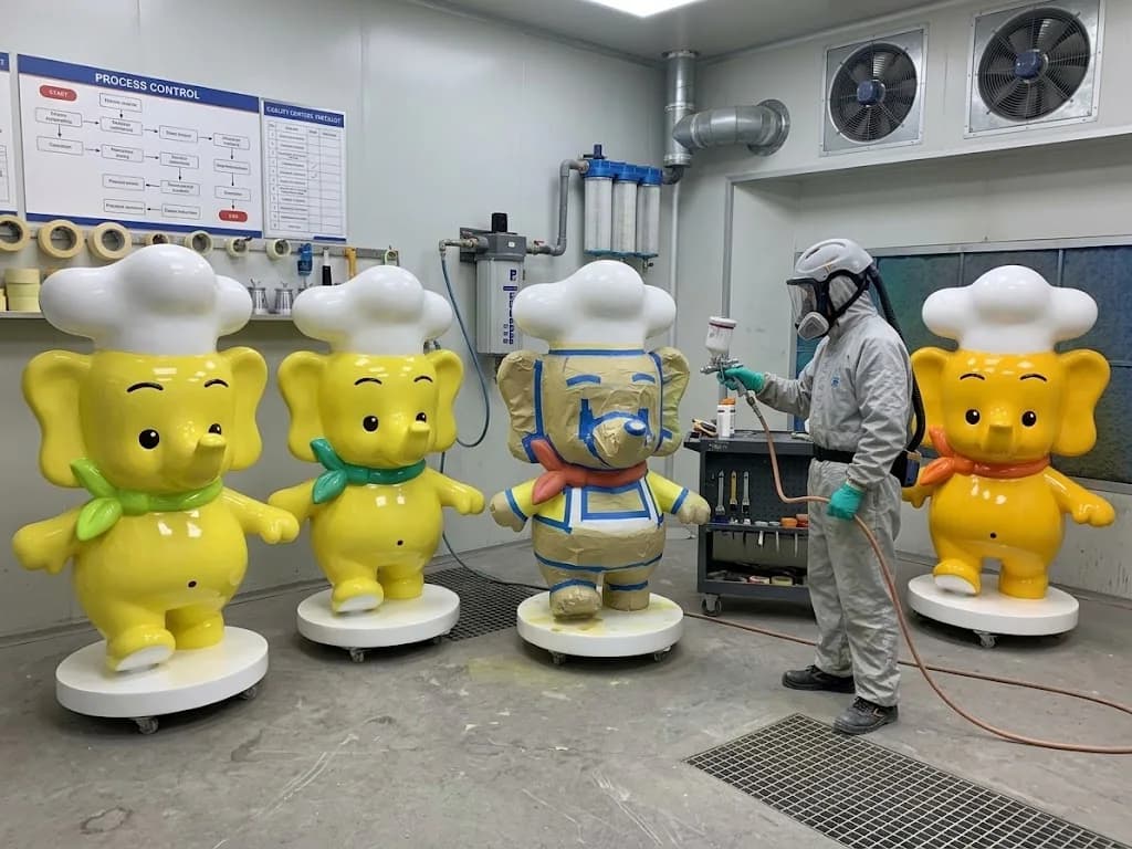 Fiberglass character sculptures undergoing spray finishing in YAVIS production workshop